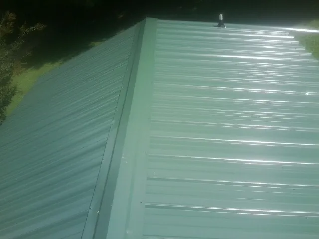 New green metal panels meeting at the ridge of a roof — Flat Roof Repair work by our crew in Denison
