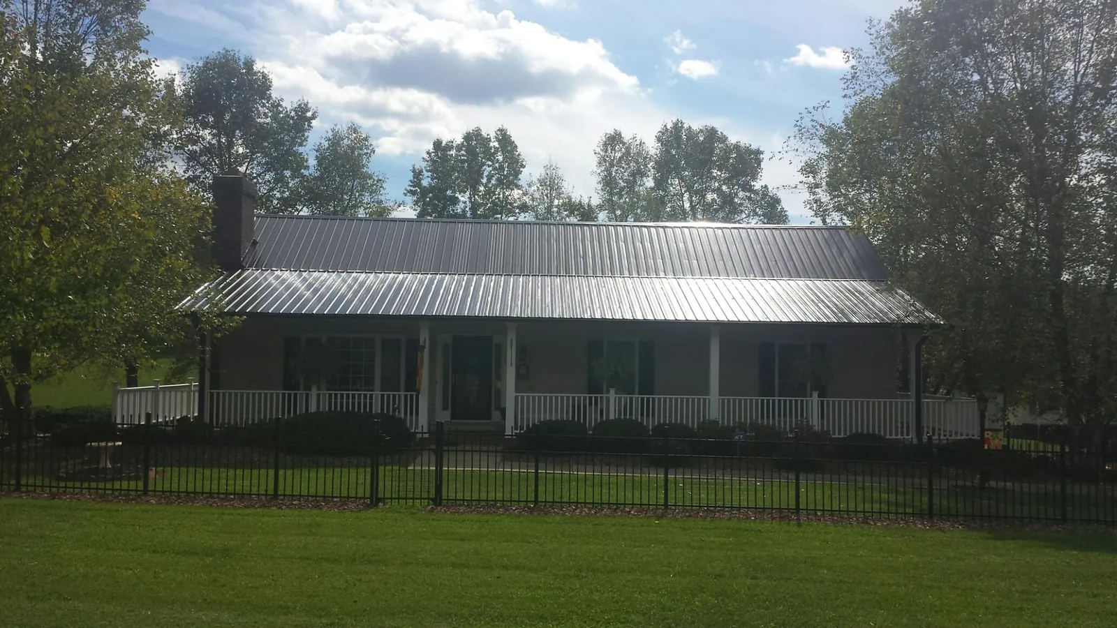 Gray metal roof on a brick ranch with a full width front porch — Gutter Guard Installation work by our crew in Denison